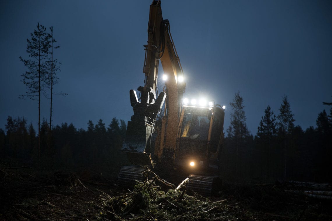 Ilta muuttuu yöksi. Sade vihmoo. Kaivinkoneen kuljettaja tekee työtään. Edessä on vielä viitisen tuntia metsänpohjan mätästystä.